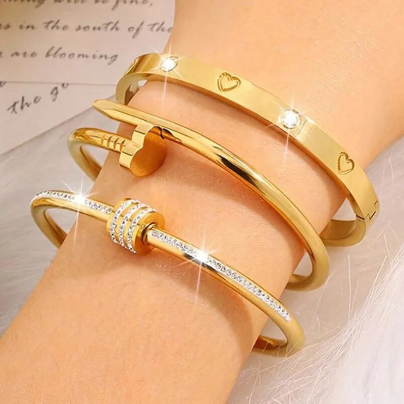 Gold bracelets with heart and star designs on a wrist against a soft background