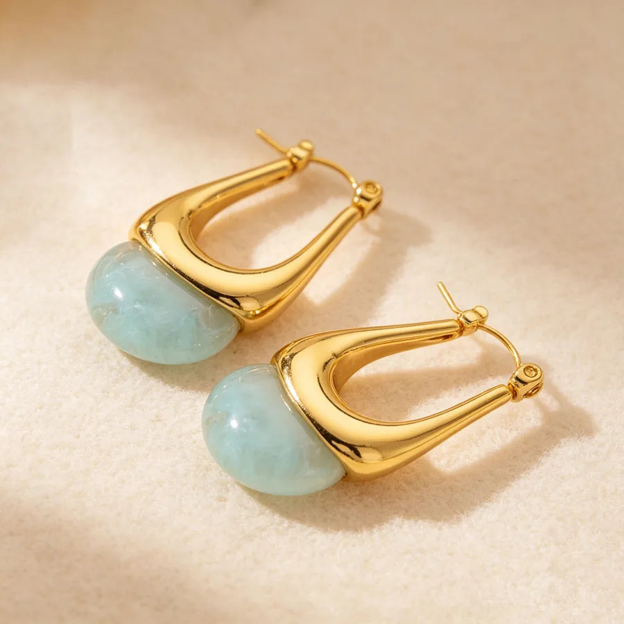 Gold hoop earrings with turquoise stones on a beige background