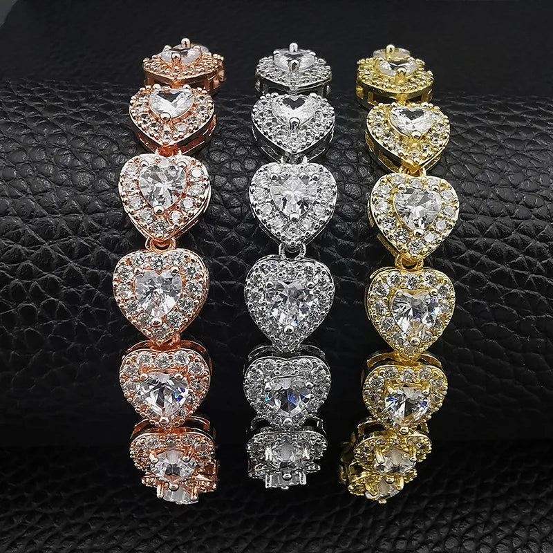 Three pairs of heart-shaped diamond earrings in rose gold, silver, and yellow gold on a black textured background.
