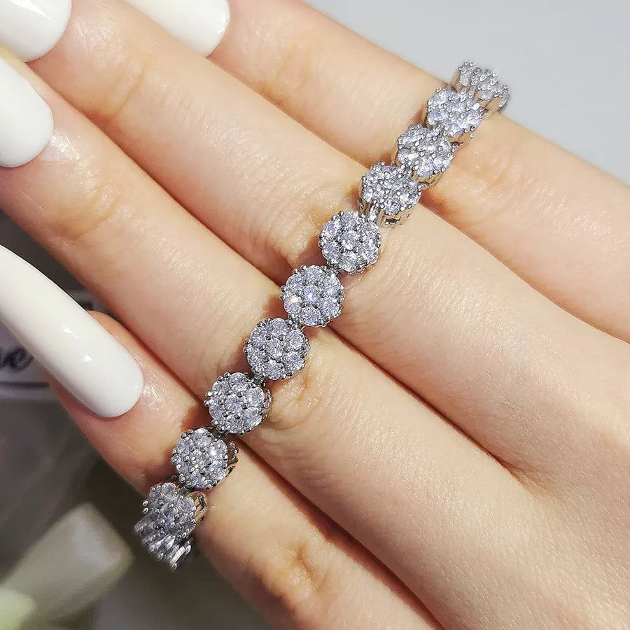 Silver bracelet with round diamonds on a hand with white nail polish.