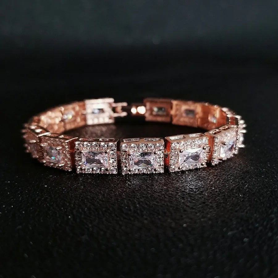 Rose gold bracelet with square-cut gemstones on a dark background