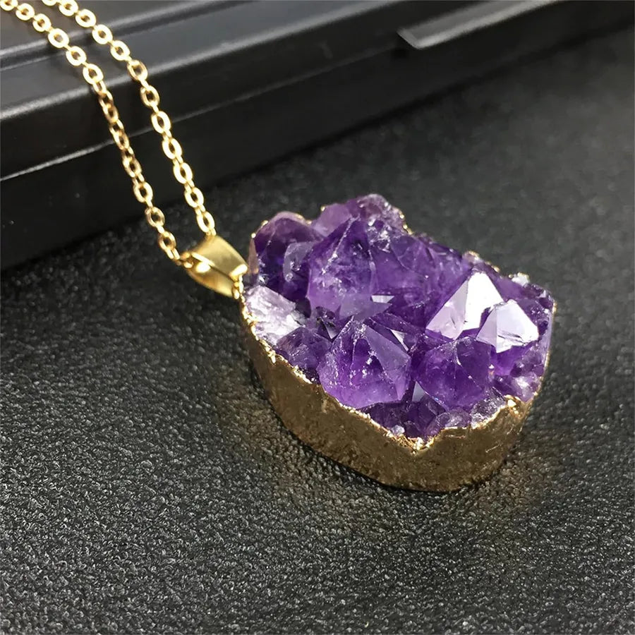 Purple crystal necklace with gold chain on a dark surface