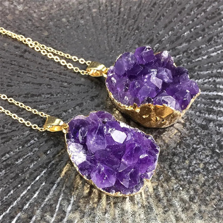 Two purple crystal necklaces with gold accents on a dark surface