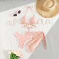 Pink lace bikini set with sunglasses, straw hat, and flowers on a white surface