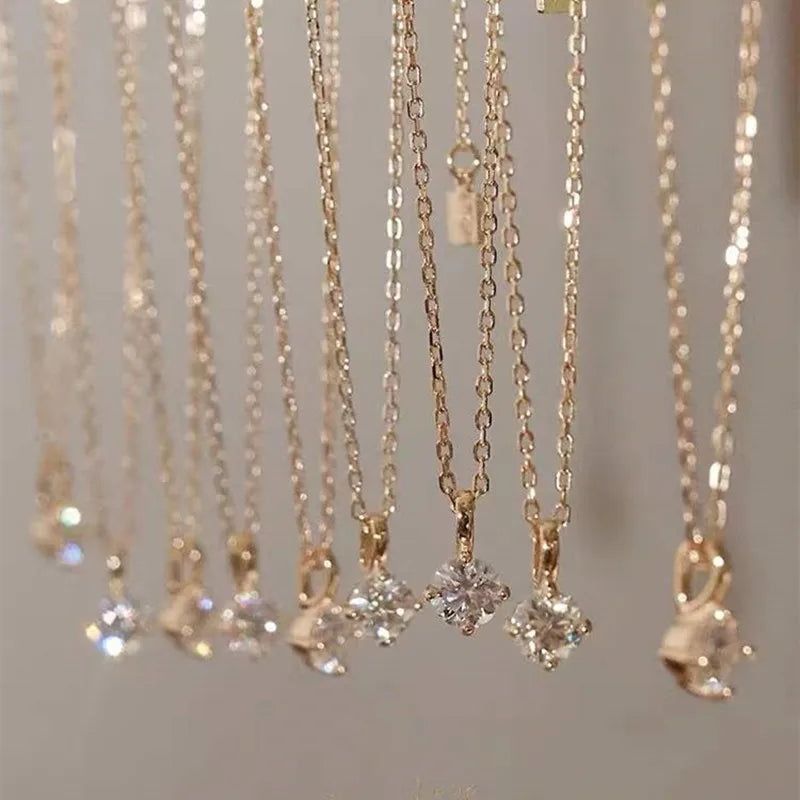 Gold necklaces with diamond pendants on a neutral background