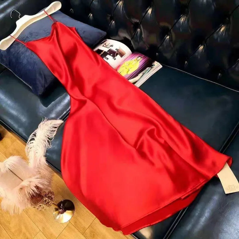 Red dress on a hanger on a black leather couch with magazines underneath.
