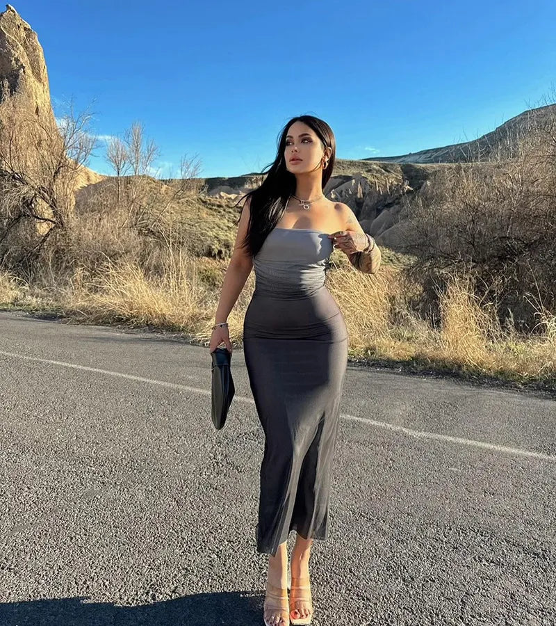 Woman in a gray dress standing on a road with mountains in the background. Vacation resort dress