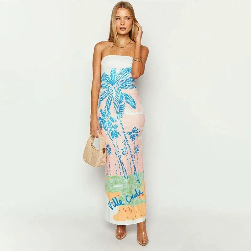 Woman wearing a strapless dress with palm tree design on a white background. Vacation resort dress
