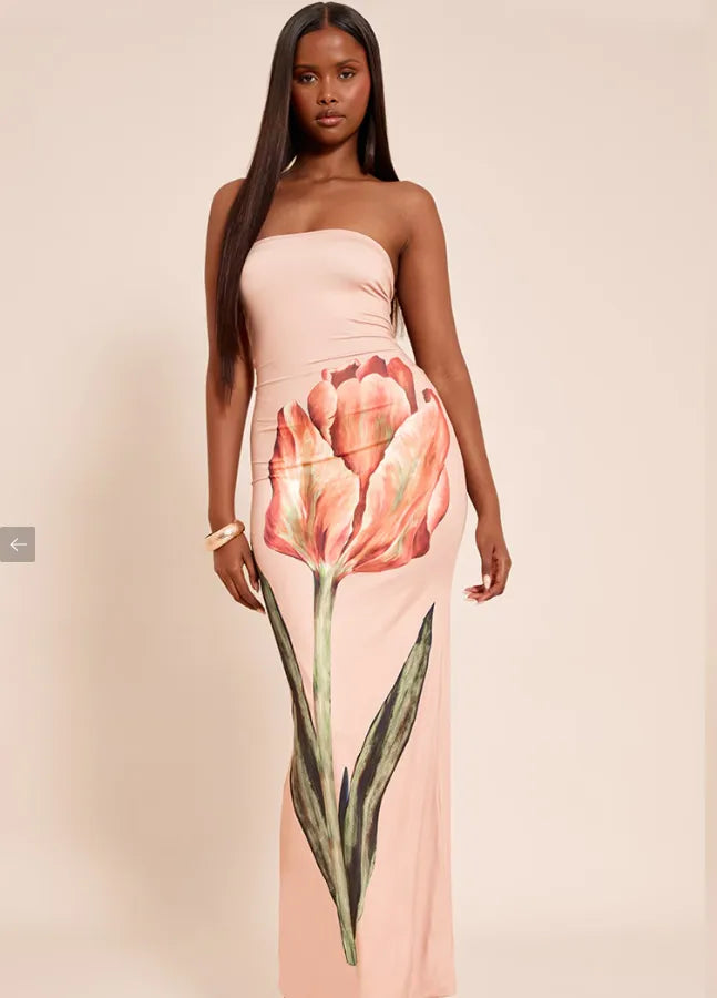 Woman wearing a strapless dress with a floral design on a beige background. Vacation resort dress