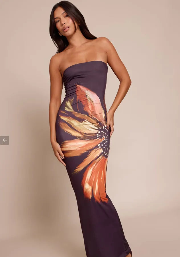 Woman wearing a strapless dress with a colorful abstract design on a beige background. Vacation resort dress