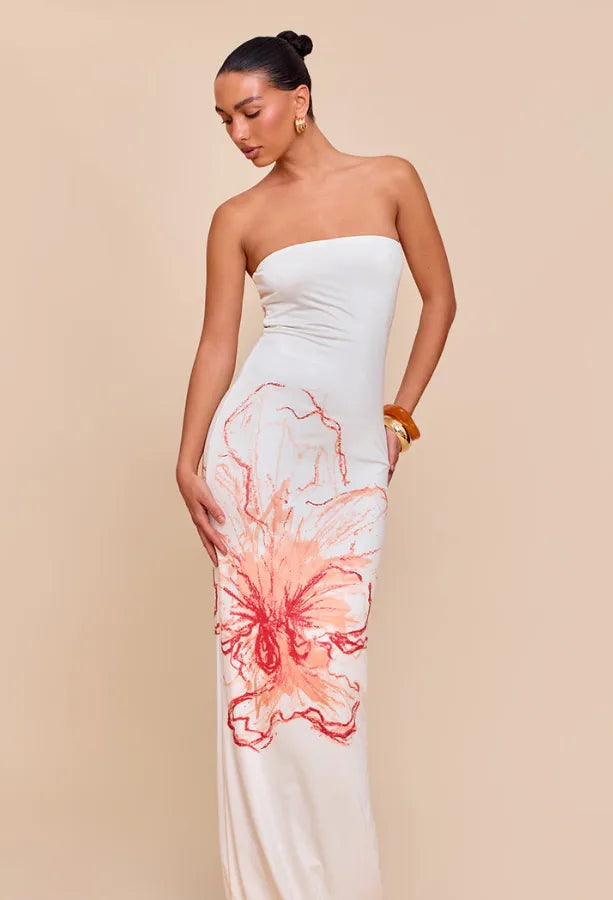 Woman wearing a strapless dress with floral design on a beige background. Vacation resort dress