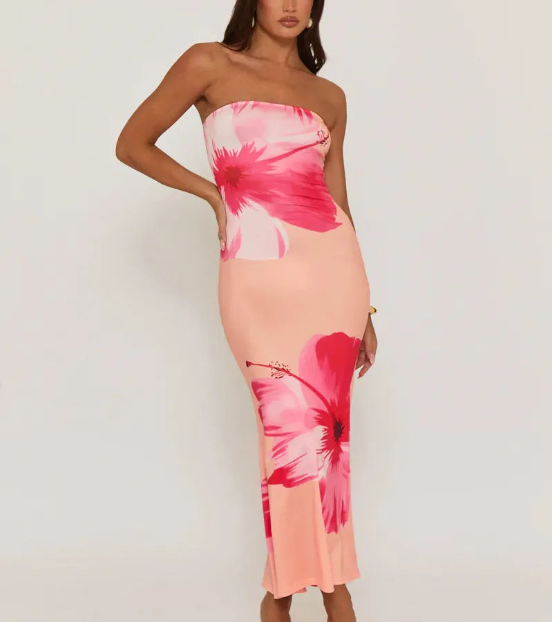 Woman wearing a strapless dress with pink floral pattern on a white background. Vacation resort dress