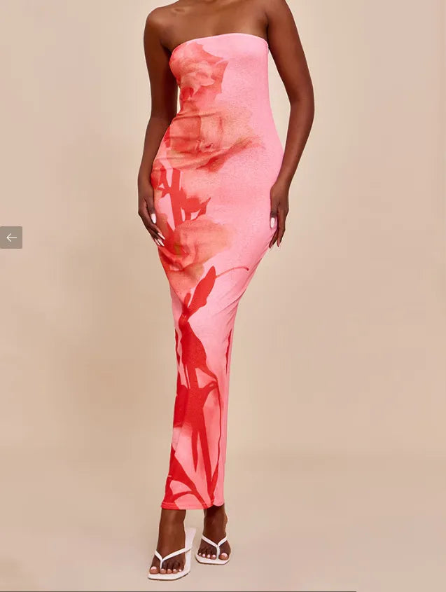 Woman wearing a strapless pink dress with a watercolor pattern on a beige background. Vacation resort dress
