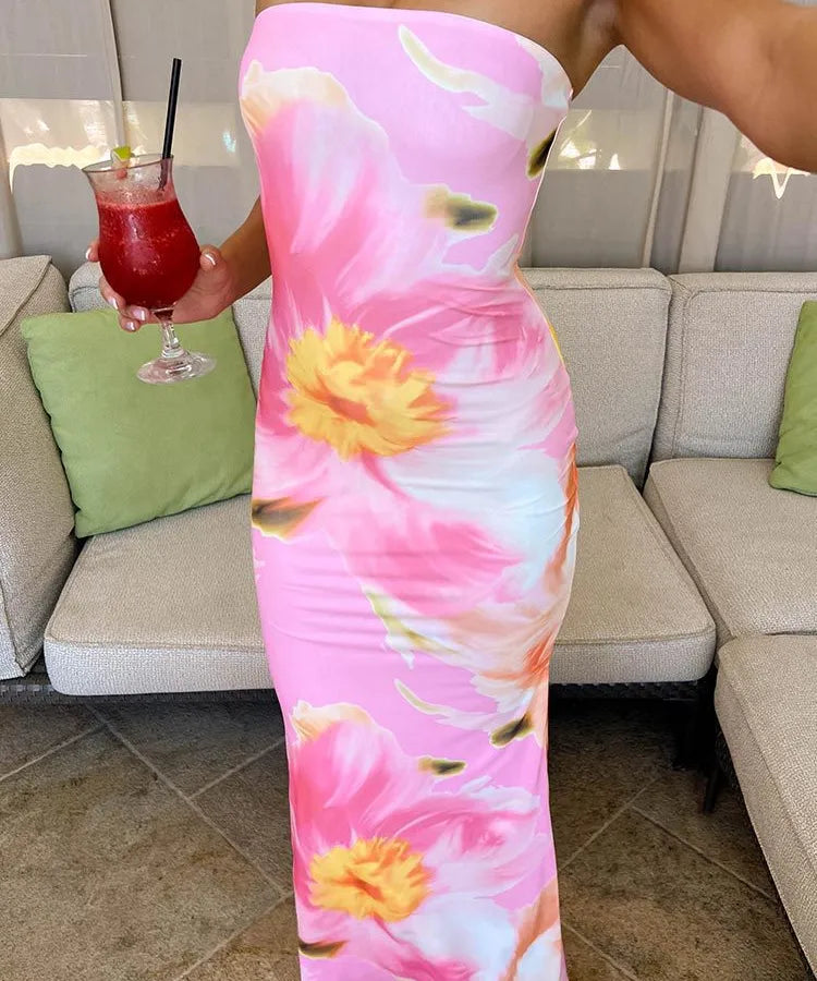 Person wearing a pink floral dress holding a red drink in a living room. Vacation resort dress