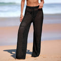 Person wearing black crochet pants on a beach Women's Hollow-Out Crochet Beach Cover-Up Pants – Sheer Wide Leg Swim Cover-Up Trousers for Resort & Vacation Wear beach cover up pants, crochet beach pants, hollow out pants, swim cover up pants, resort wear women, wide leg beach pants, crochet cover up, vacation outfit, poolside cover up, sheer beach pants, beachwear women, cruise outfit, tropical vacation clothes, boho beach pants, crochet trousers