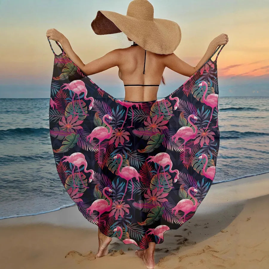 Woman on a beach wearing a floral patterned sarong with flamingos and palm trees.