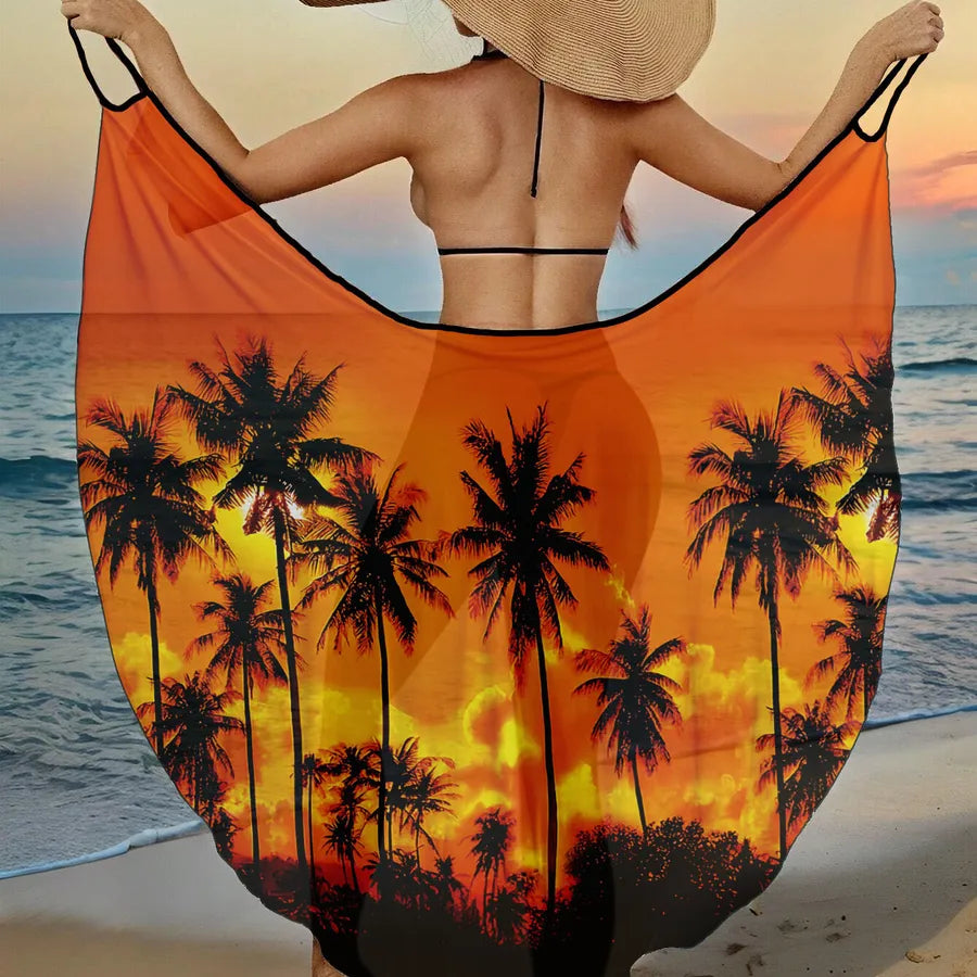 Person holding an orange beach towel with palm tree design on a beach at sunset.