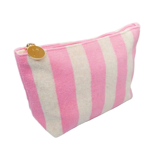 Pink and white striped pouch with a gold tag on a light wooden surface