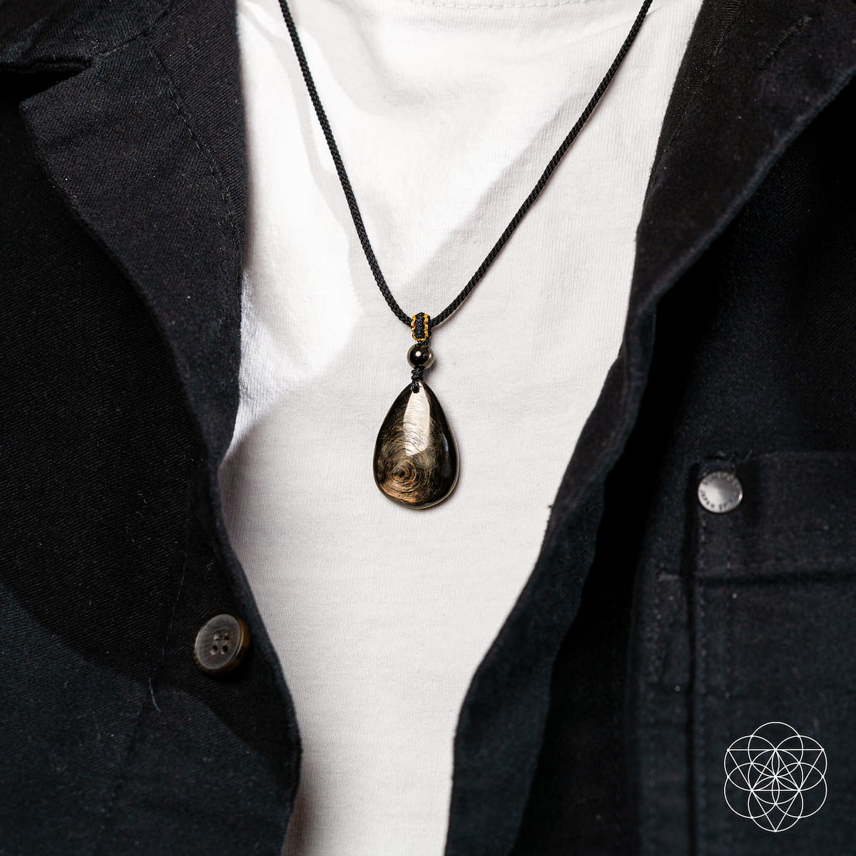 Necklace with a pendant worn by a person in a black jacket and white shirt. The ﻿Hypersthene Millionaire Manifestation Pendant. Rare Egyptian Wealth Stone.