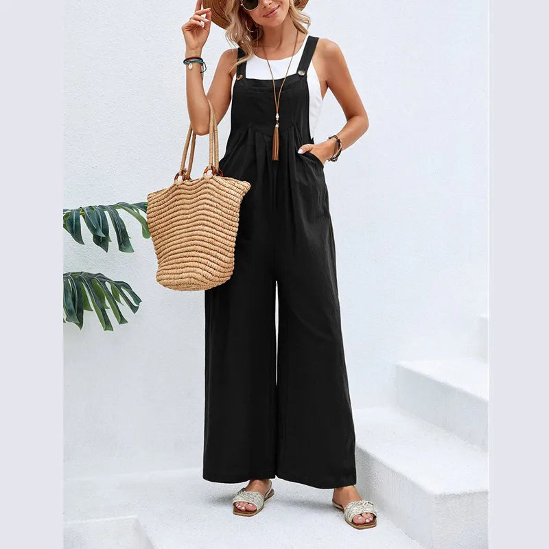Woman wearing a black jumpsuit holding a straw bag against a white background