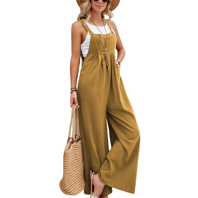 Woman wearing a mustard yellow jumpsuit with a white top, holding a straw bag on a white background.