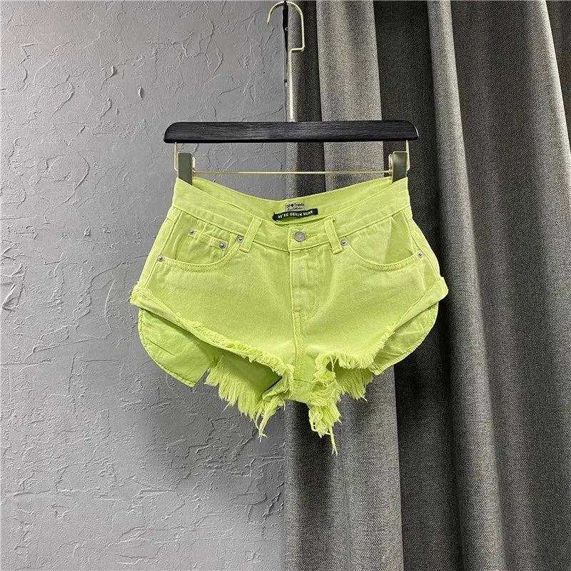 Neon green denim shorts on a hanger against a gray curtain background