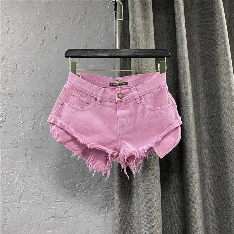 Pink denim shorts on a hanger against a gray curtain background