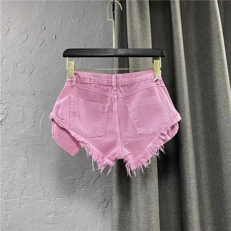 Pink denim shorts on a hanger against a gray curtain background