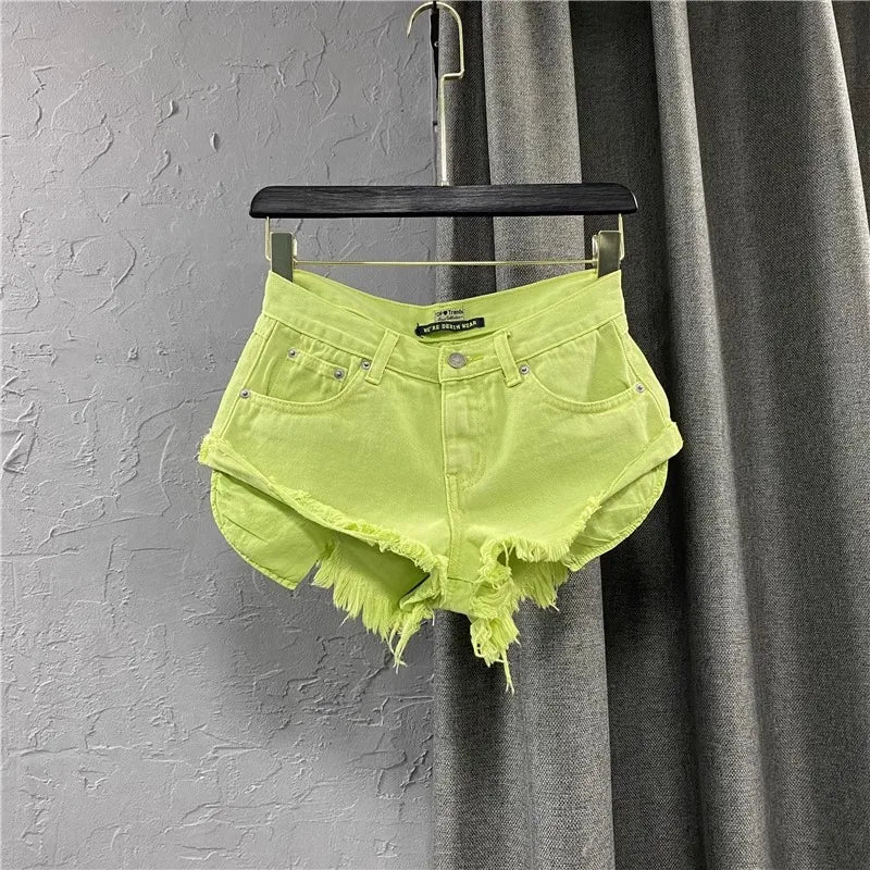 Neon green denim shorts on a hanger against a gray curtain background