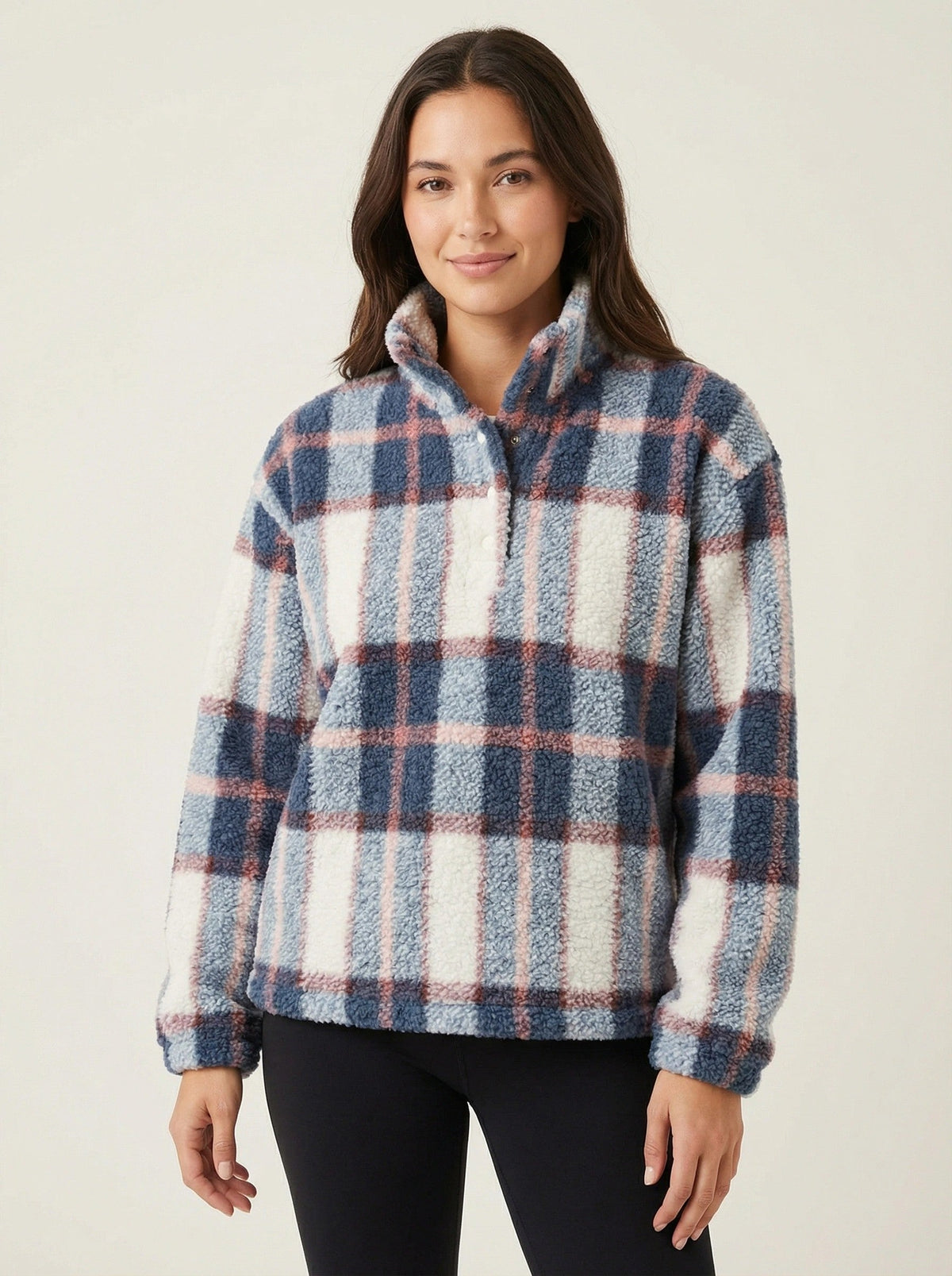 Woman wearing a plaid pullover against a plain background