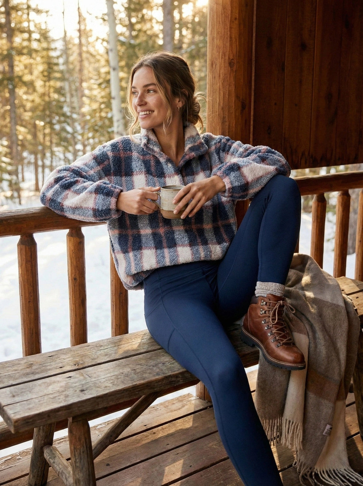 Woman sitting on a wooden bench outdoors, holding a mug, wearing a plaid shirt and blue pants.