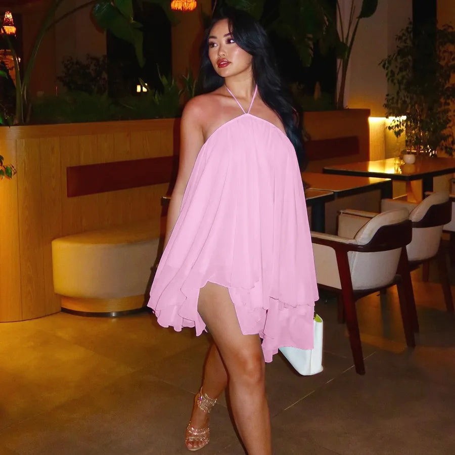 Woman in a pink dress standing in an indoor setting with plants and furniture.