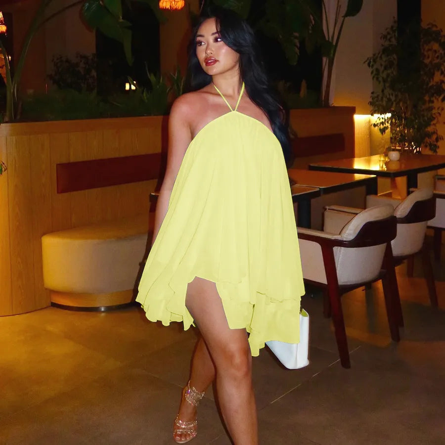 Woman in a yellow dress standing in an indoor setting with plants and furniture.