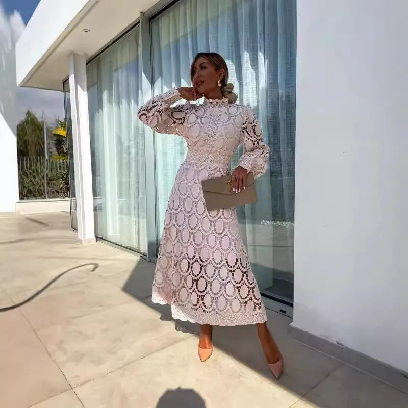 Woman in a white lace dress standing outside a modern building.