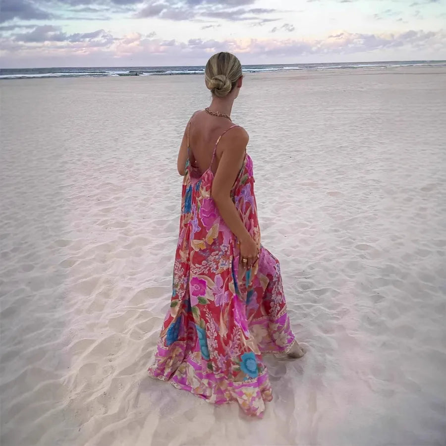 Woman in a colorful dress standing on a sandy beach with ocean in the background