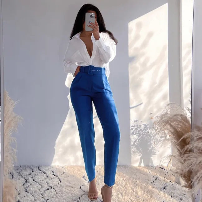 Person wearing a white blouse and blue pants standing in front of a mirror. high waisted pants women, pleated trousers women, ankle length pants, slim fit trousers, business casual pants, work pants women, office trousers, women's dress pants, casual chic outfit, tailored pants women, everyday trousers, spring fashion women, autumn pants women, elegant trousers, commuter style fashion, women's workwear, high rise pants, fashion trousers women, travel pants women, versatile wardrobe essentials