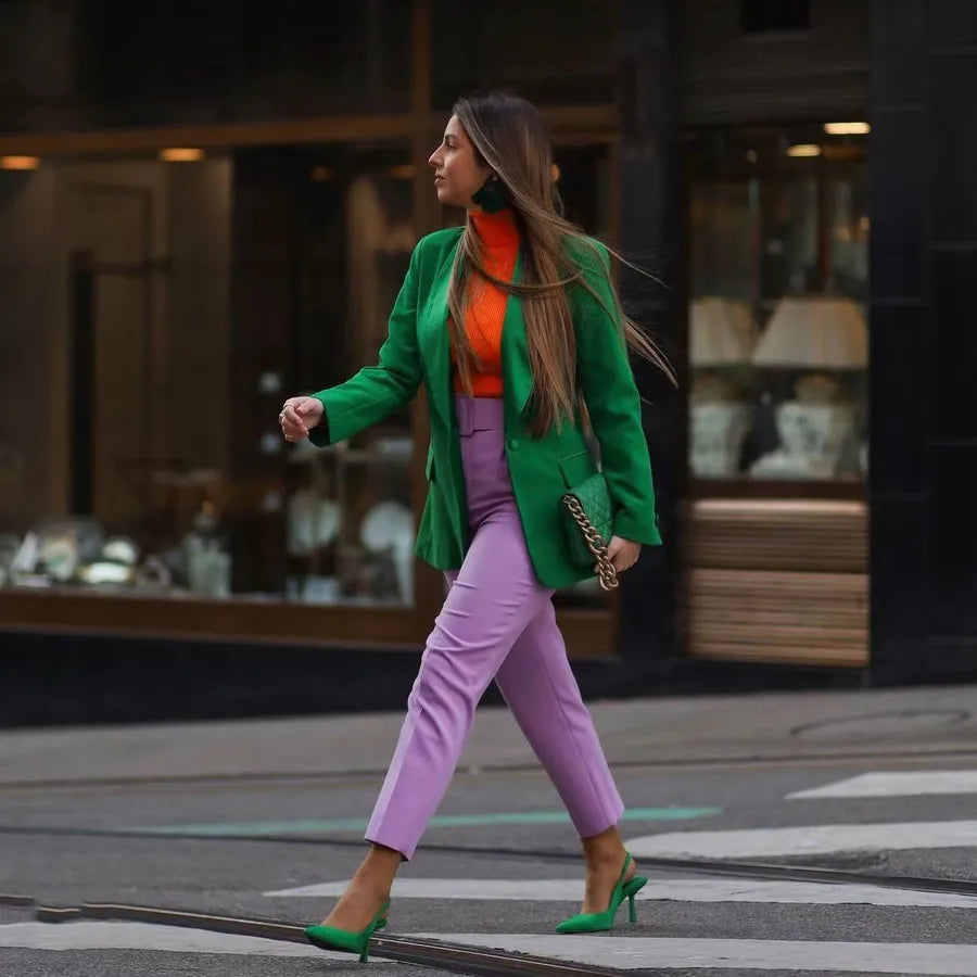 Woman in a green jacket and purple pants crossing a street. high waisted pants women, pleated trousers women, ankle length pants, slim fit trousers, business casual pants, work pants women, office trousers, women's dress pants, casual chic outfit, tailored pants women, everyday trousers, spring fashion women, autumn pants women, elegant trousers, commuter style fashion, women's workwear, high rise pants, fashion trousers women, travel pants women, versatile wardrobe essentials