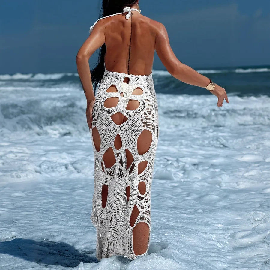 Woman wearing a white crochet dress on a beach with ocean waves in the background