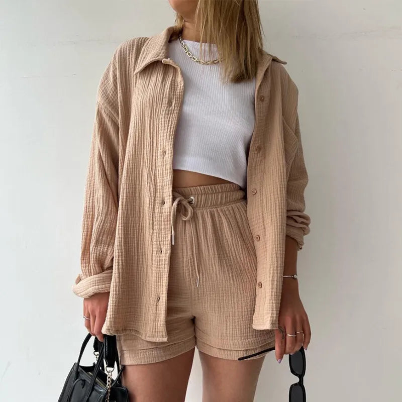 Person wearing a beige light brown shirt, white crop top, and beige light brown drawstring shorts shorts with a plain background