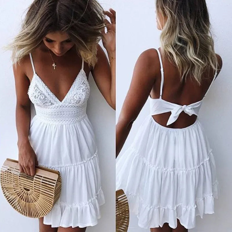 White lace dress with cut-out back worn by a model, held by a woman with a wooden handbag.