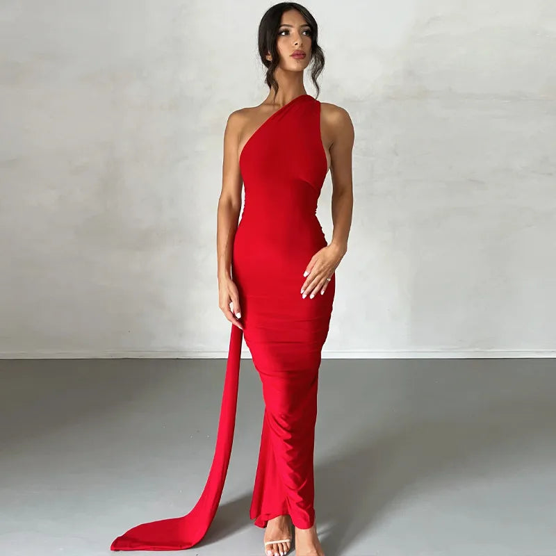 Woman wearing a red one-shoulder dress with a long train on a plain background