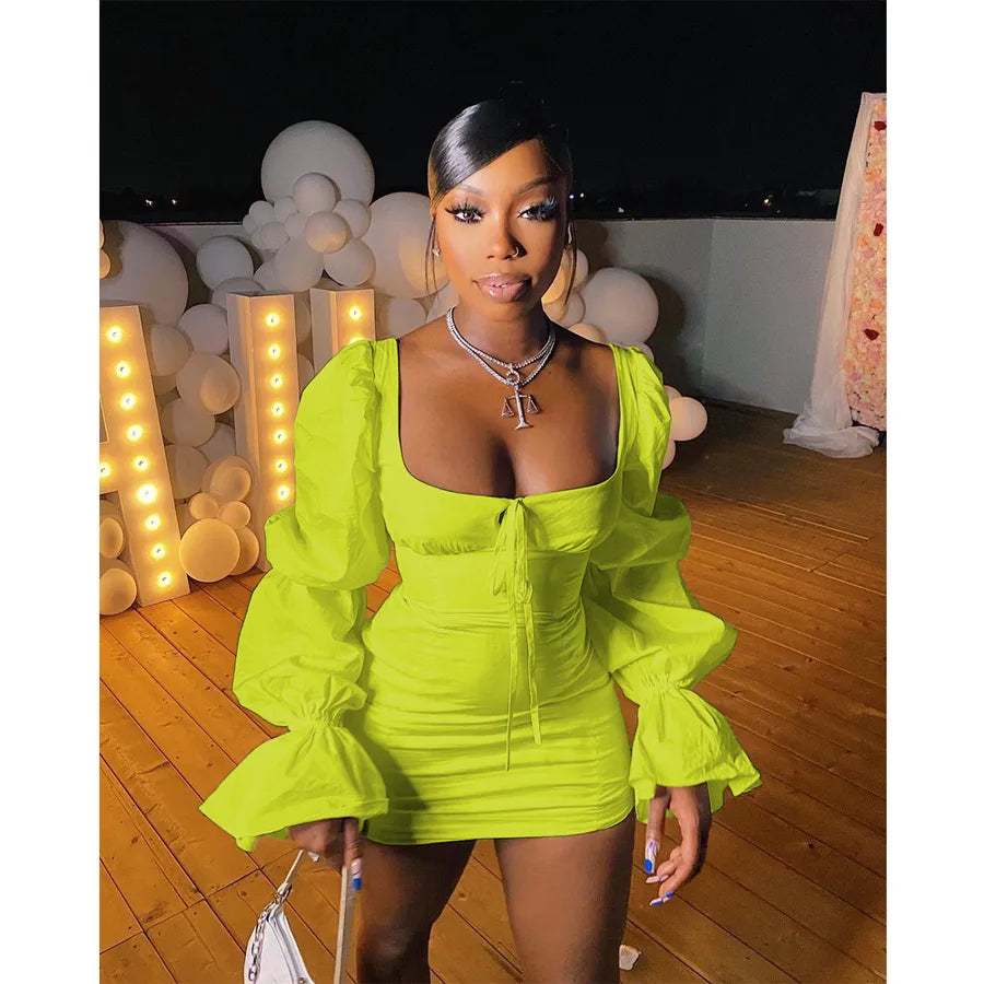 Woman in a bright green dress standing in an indoor setting with decorative lights and balloons.