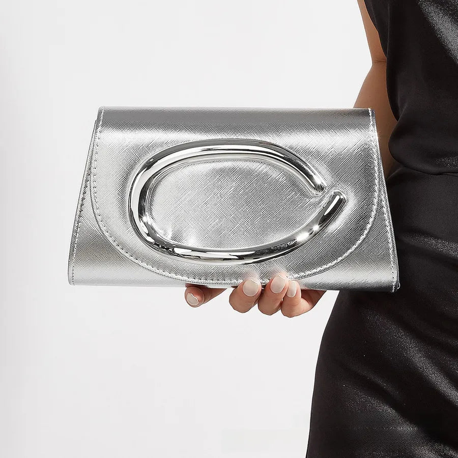 Silver clutch held by a person on a white background