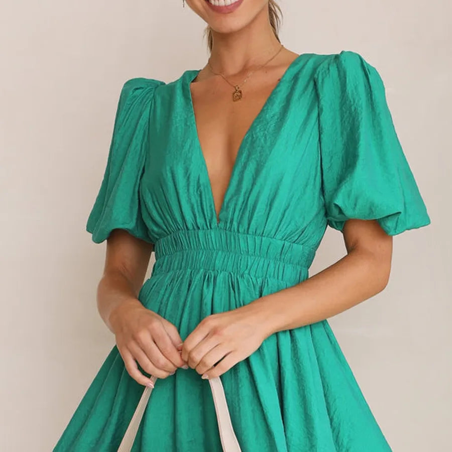Woman wearing a green dress with puff sleeves against a plain background