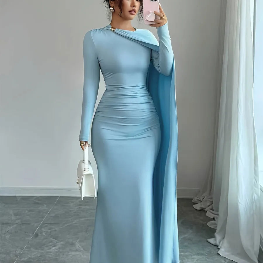 Woman in a light blue evening gown with a long train, standing in a room with white curtains.
