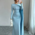 Woman in a light blue evening gown with a long train, standing in a room with white curtains.