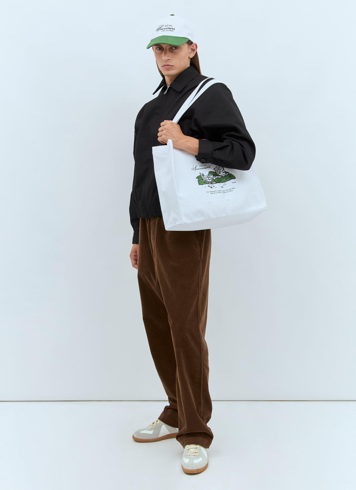 Person holding a white tote bag with a logo against a white background