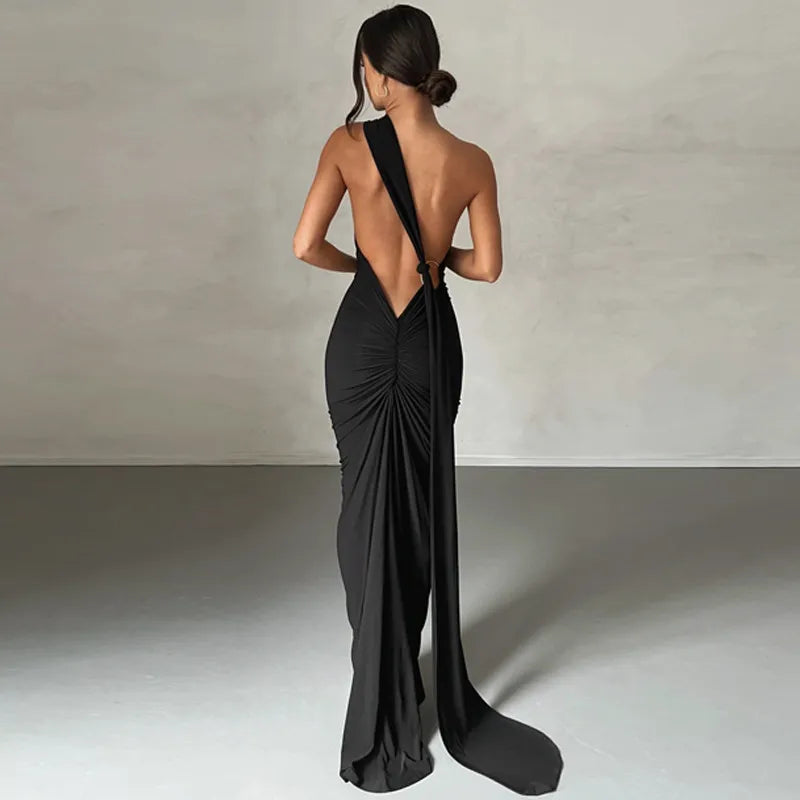 Woman wearing a black evening gown with a low back design against a neutral background