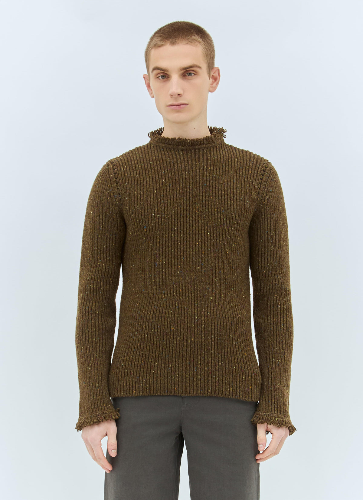 Man wearing a brown knitted sweater against a light blue background