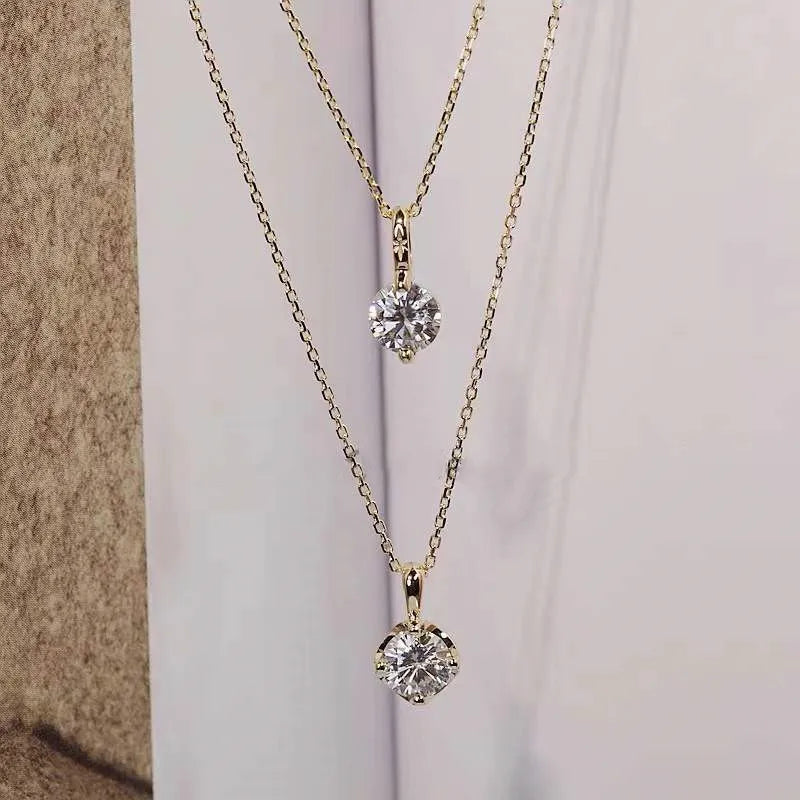 Two diamond pendants on gold chains against a neutral background